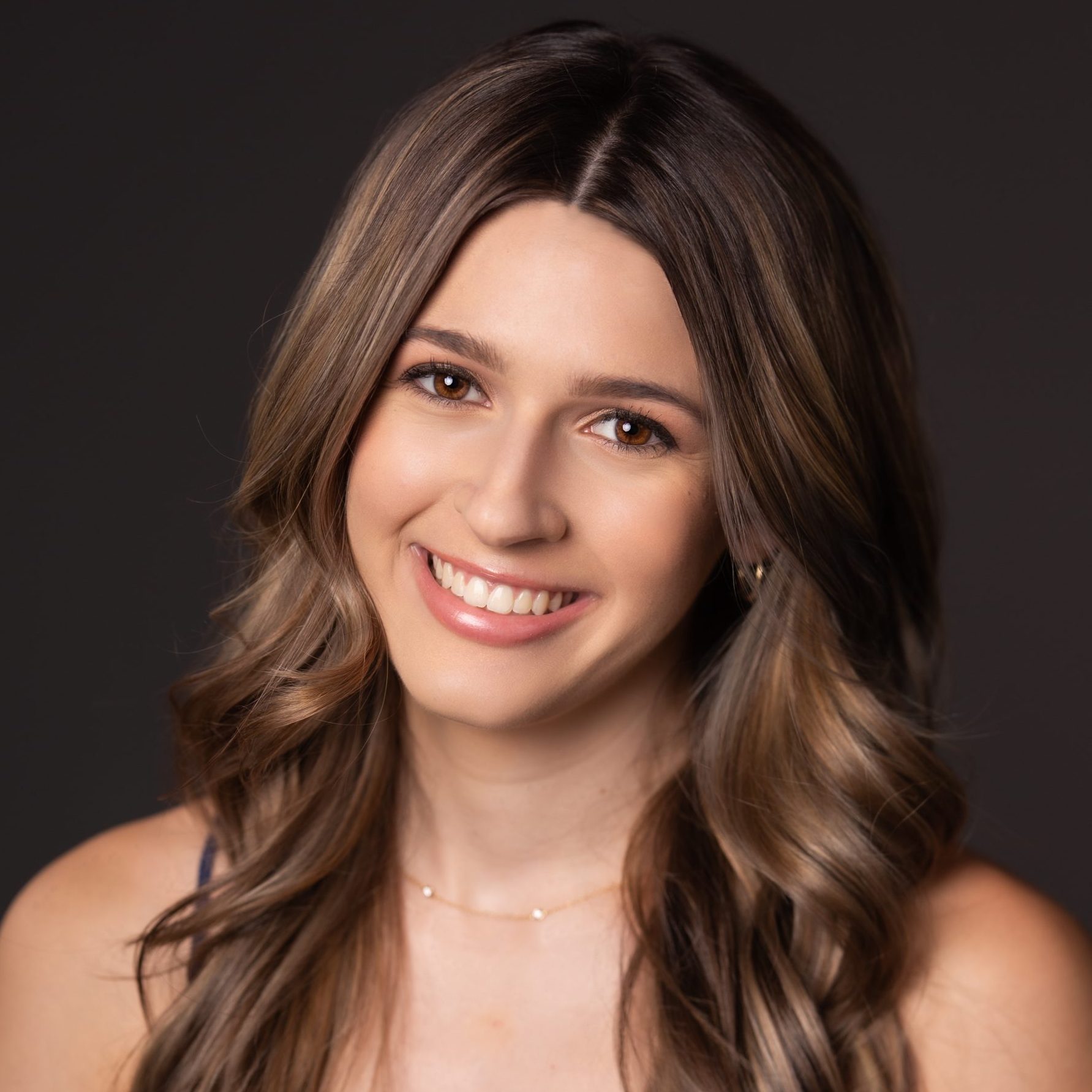 girl with shoulder length hair and brown eyes smiling at camera